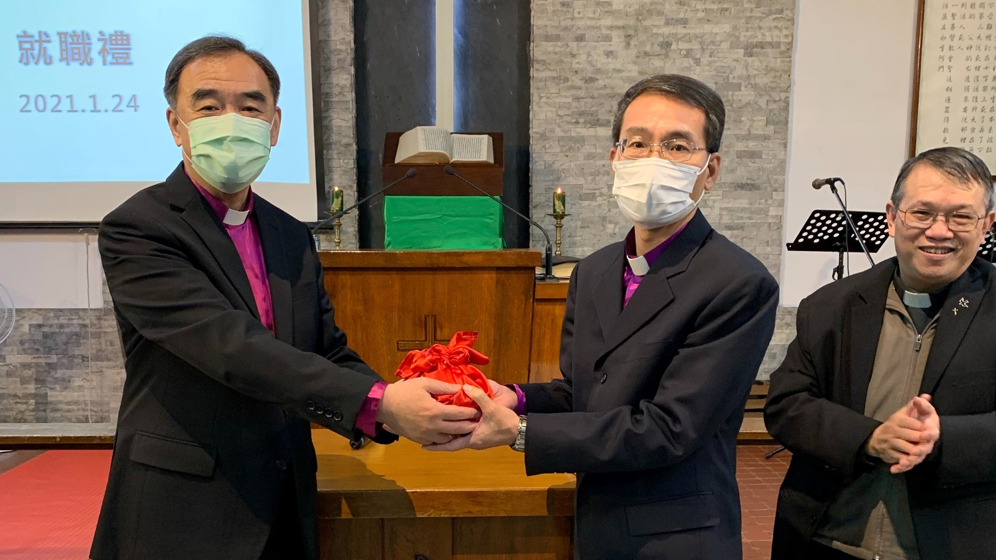 Avtroppende biskop Ray Chen (til venstre) overgir synodens stempel til sin etterfølger, Pan Li Yen. Til høyre, pastor Du Sheng En.