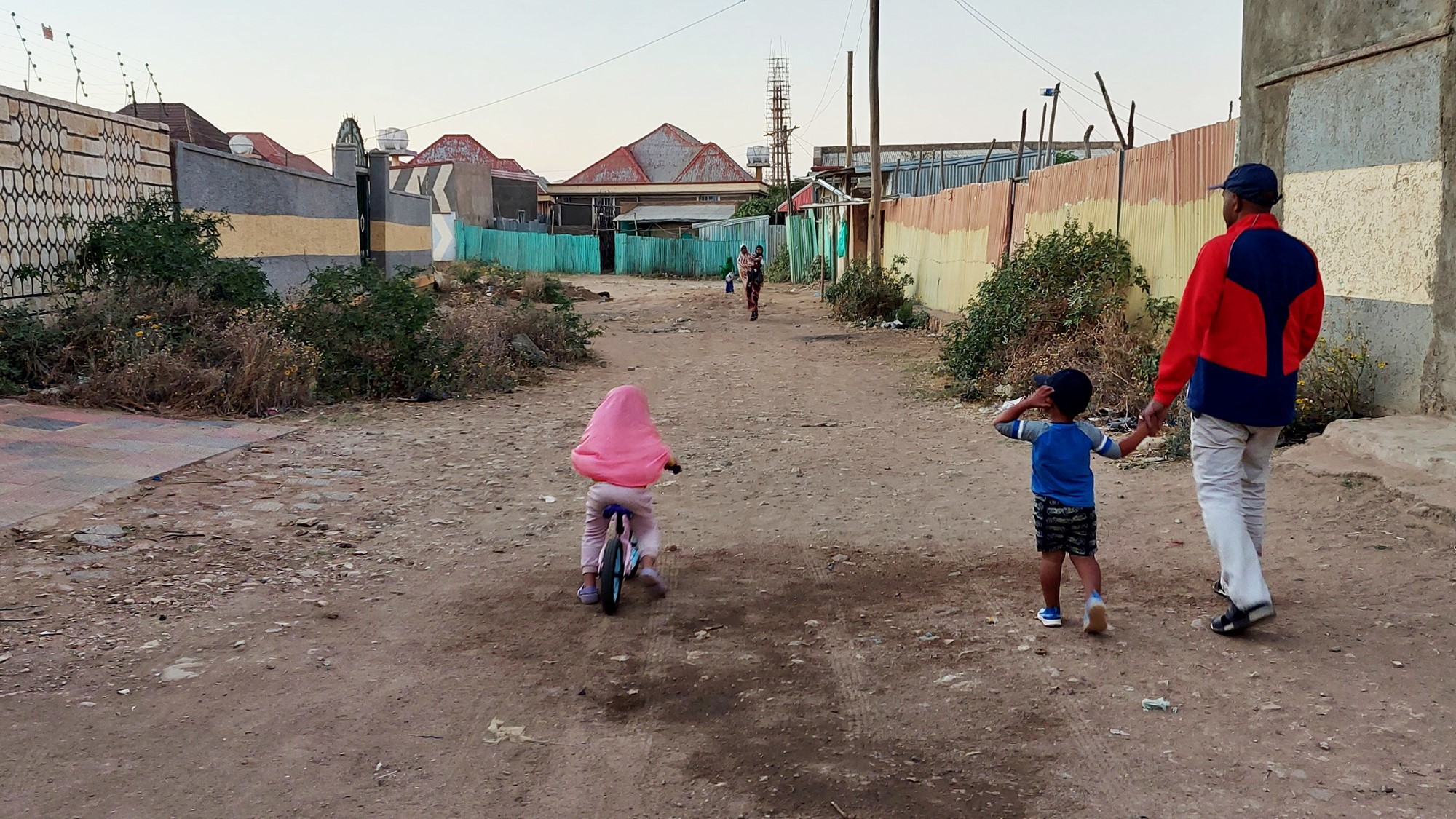 Far og barn går i støvete gate