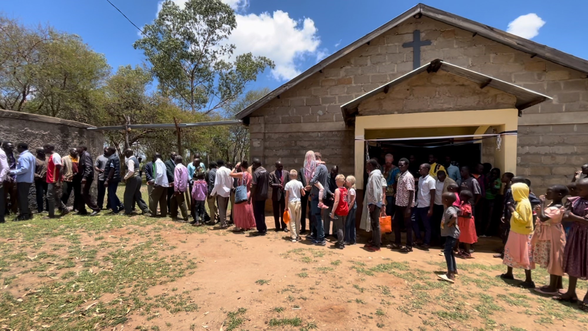 Lang kø av mennesker utenfor rural kirke
