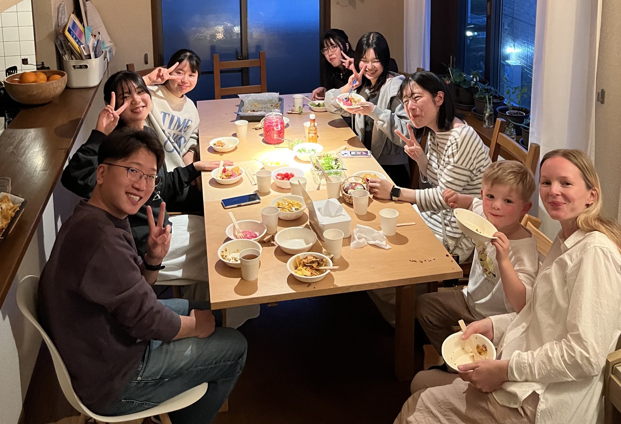 Japanske ungdommer sammen med en norsk misjonær og et barn, samlet rundt et bord.