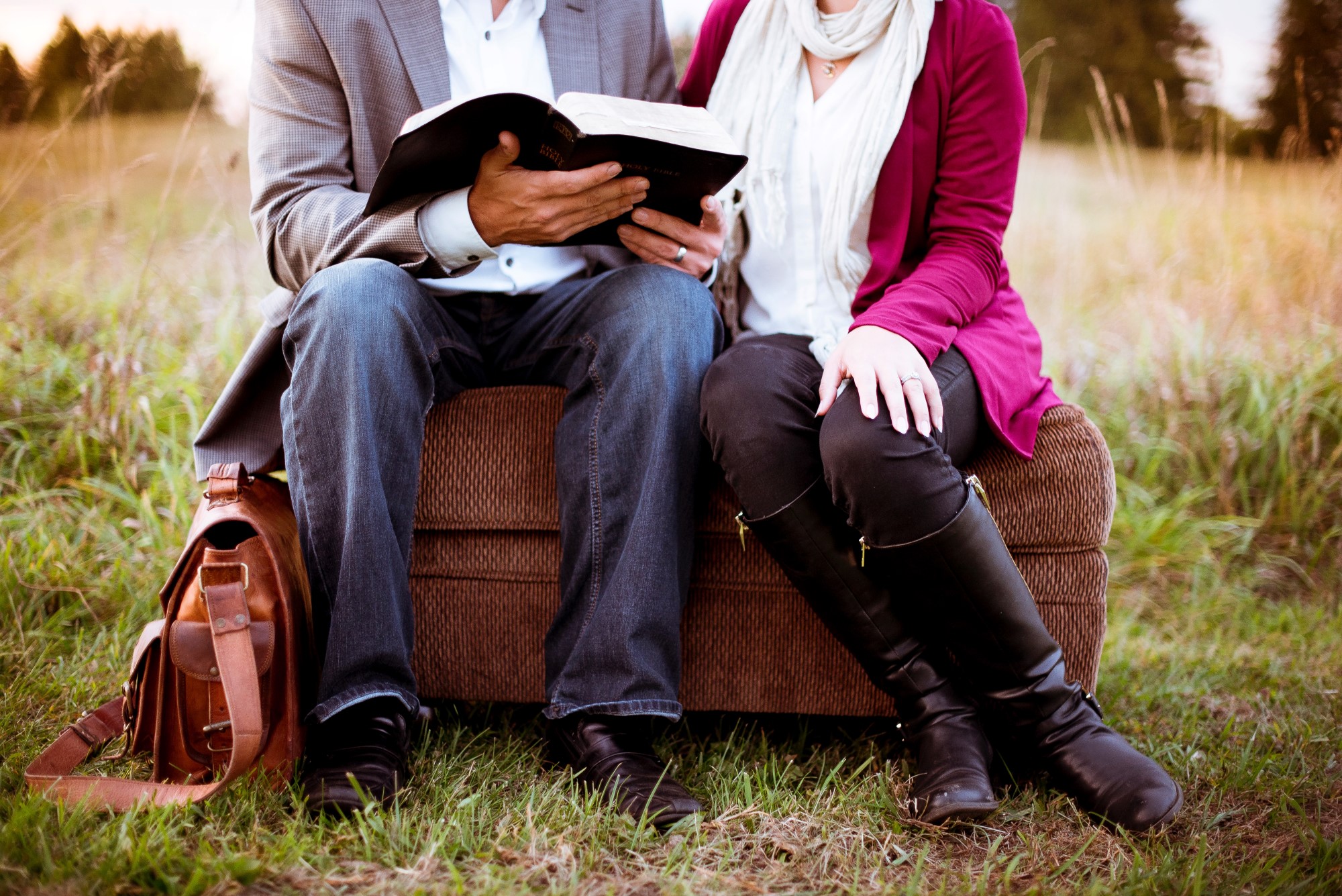 Voksne som sitter på benk og leser i bibelen