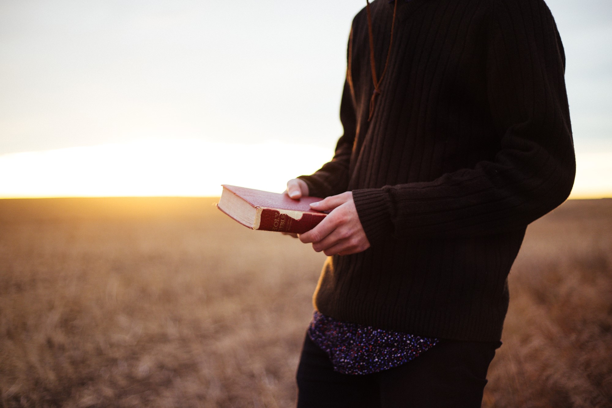 Mann leser bibel i solnedgang