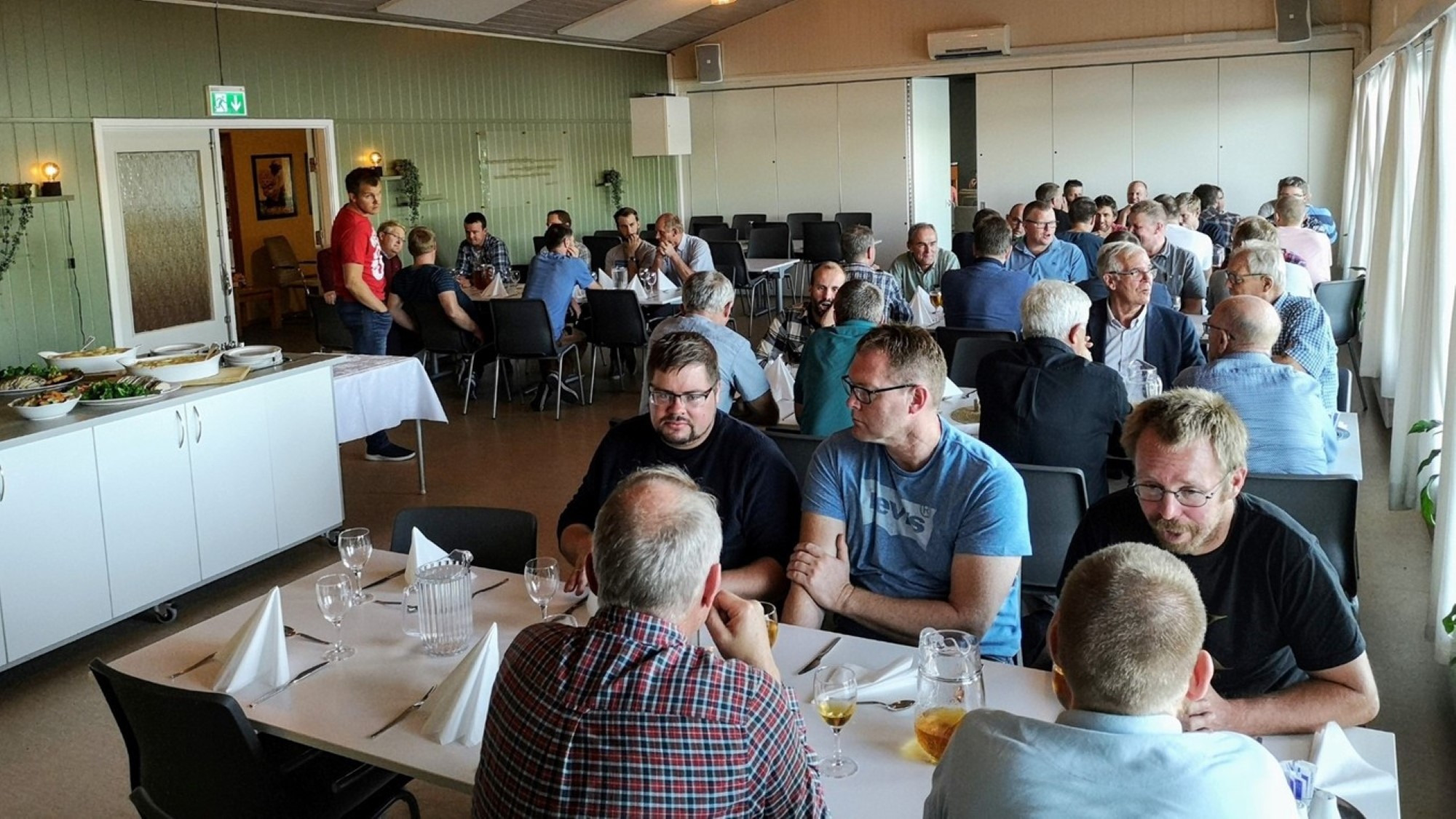 Menn rundt bord i matsal