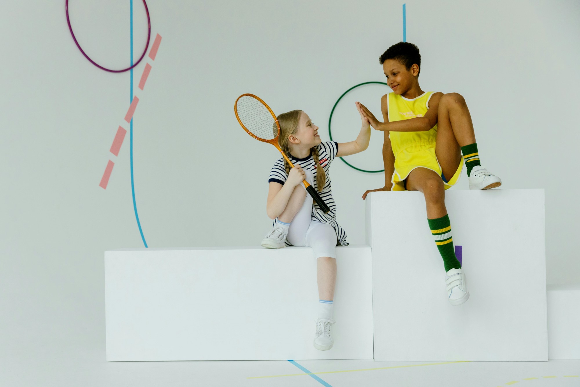 Gutt og jente tar high-five, holder tennisracket og ball