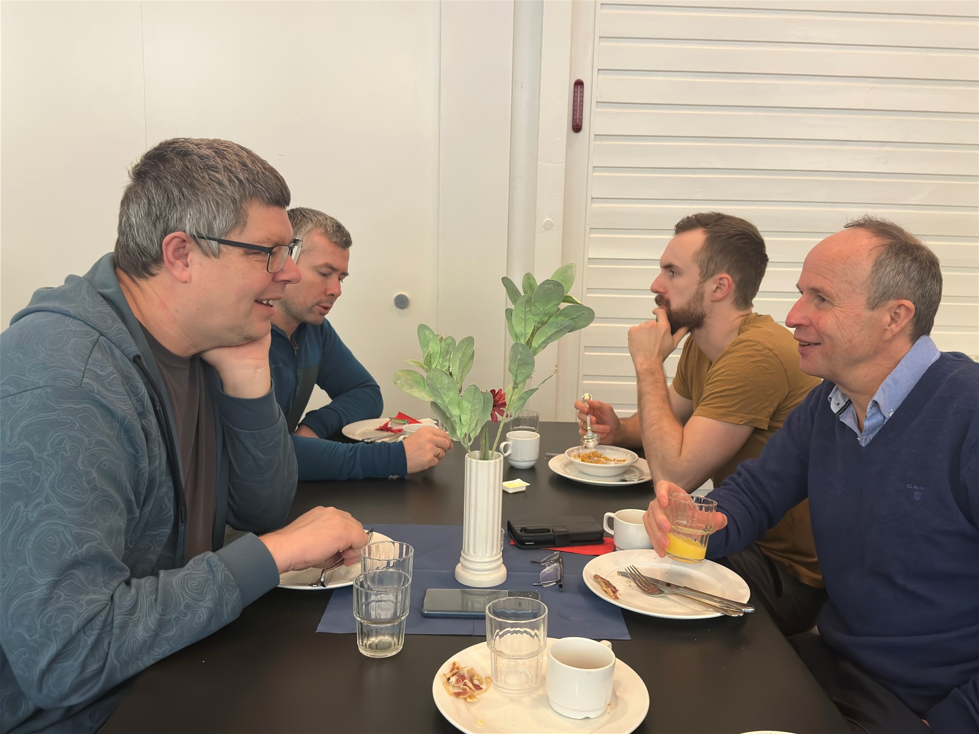 Bildet viser 4 menn som sitter rundt et bord og spiser