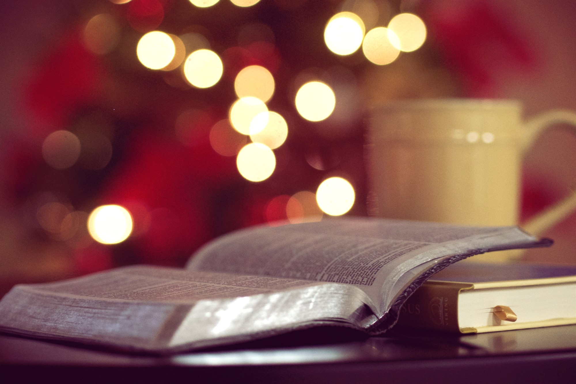 Bibel og kaffekopp i varmt julelys