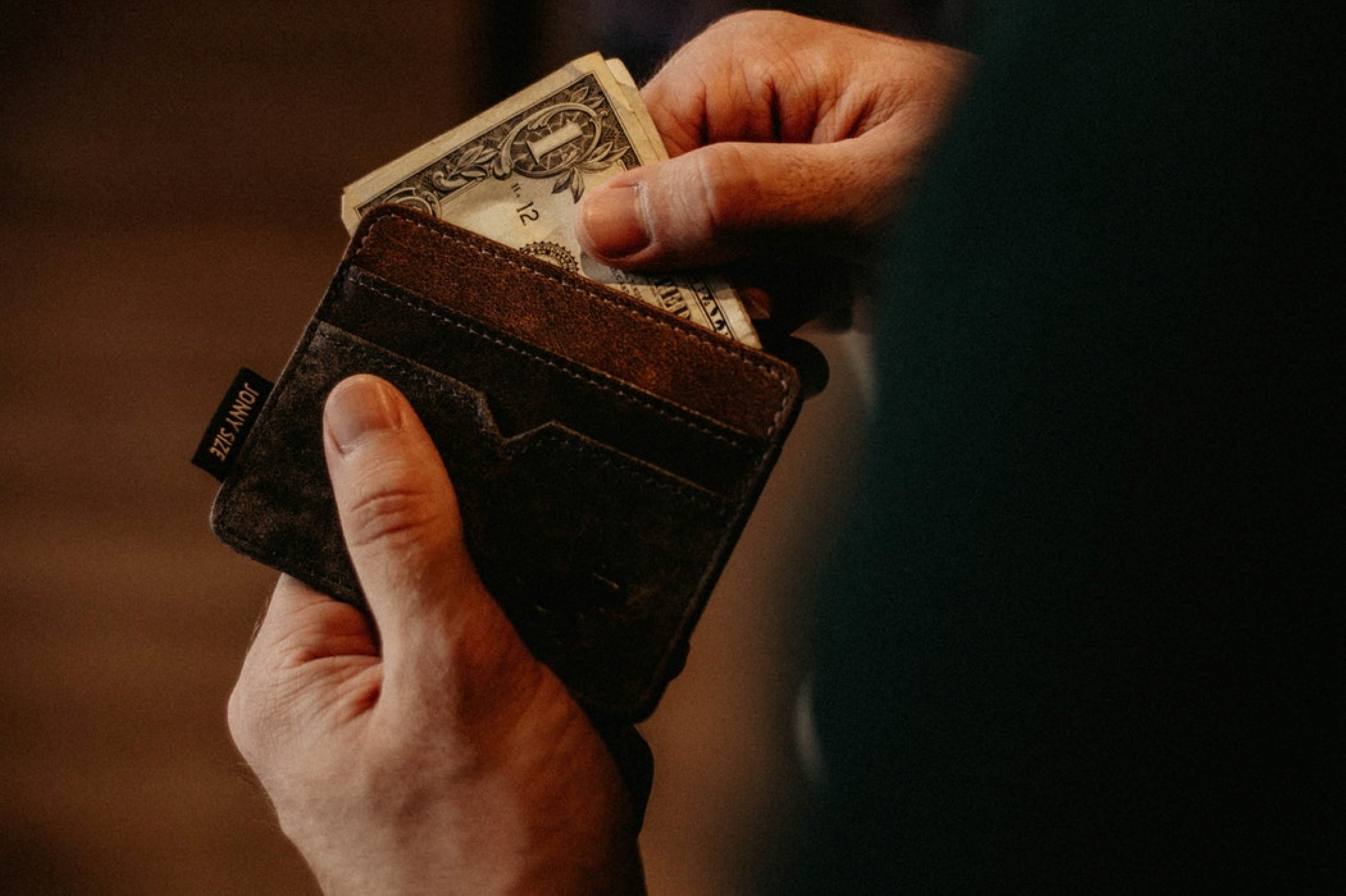Person tar ut en dollarseddel fra lommeboka