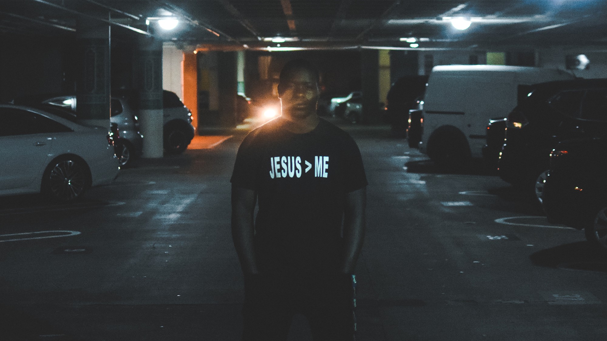 Mann i garasje iført t-skjorte med trykk "Jesus > Me"