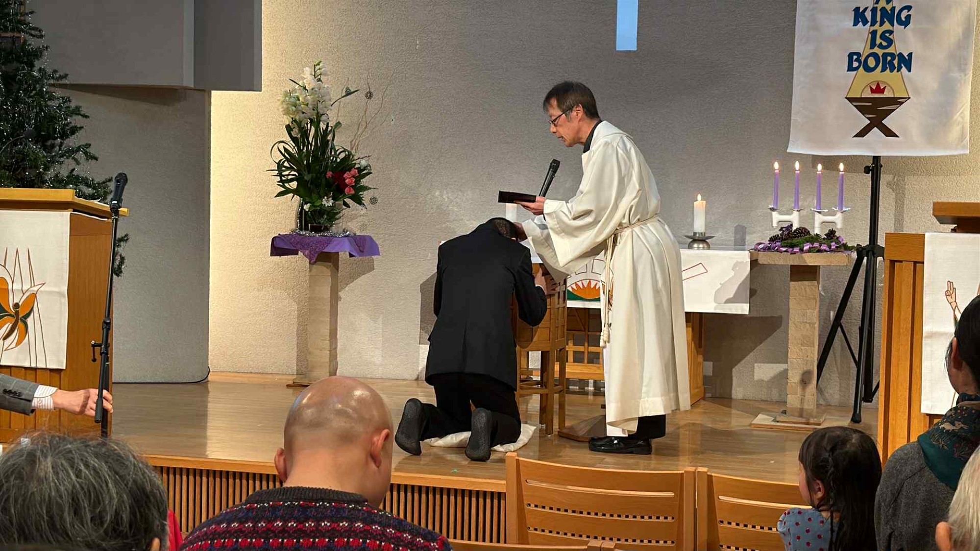 En mann kneler ned og blir døpt av en prest i en japansk kirke.