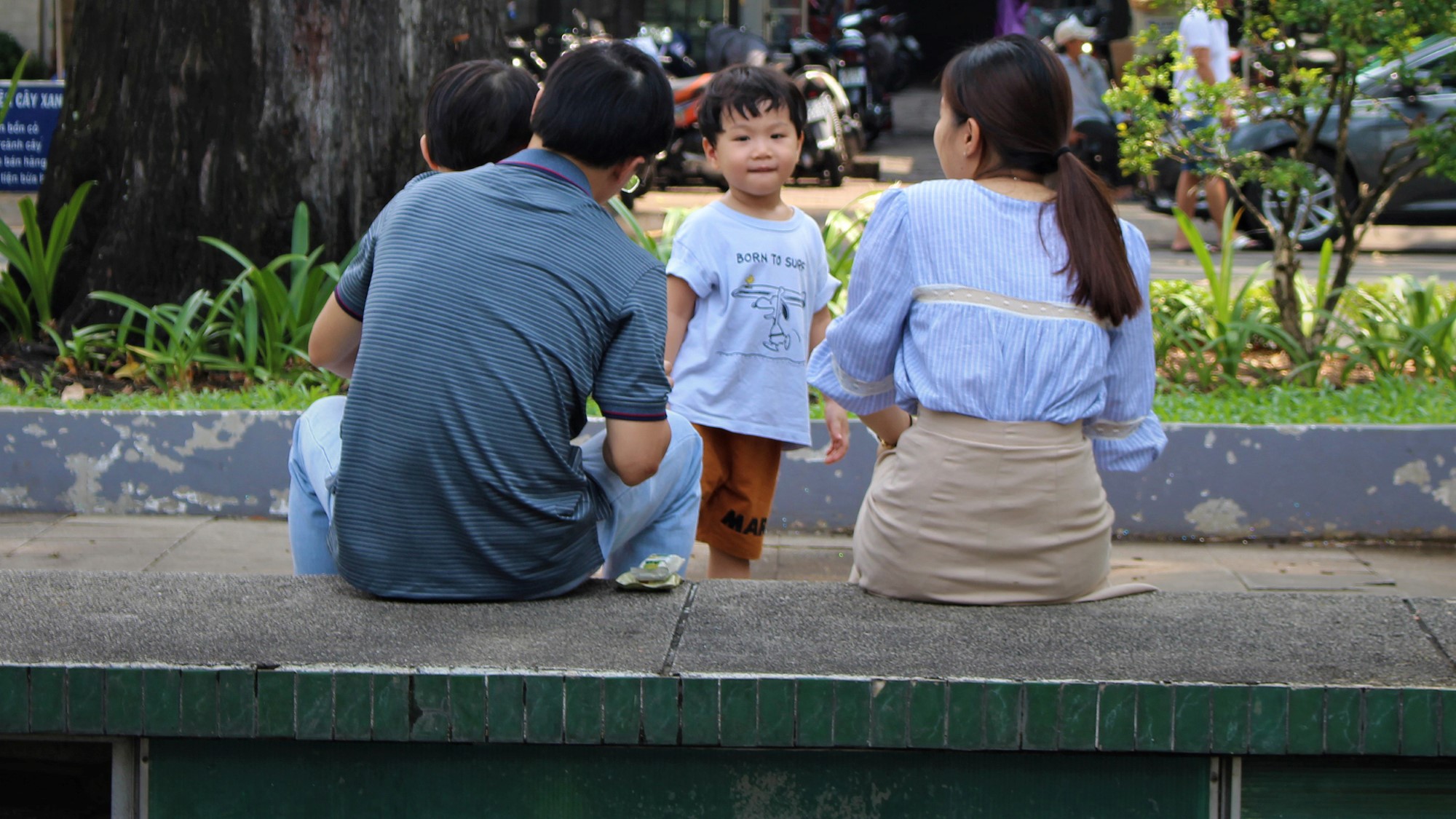 Kinesisk familie sitter på benk