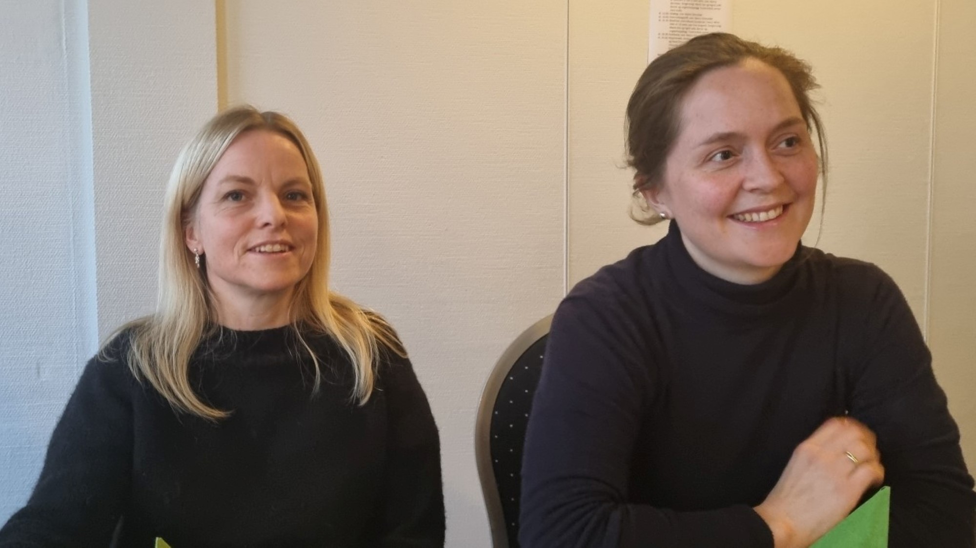 To unge, smilande damer ved bordet
