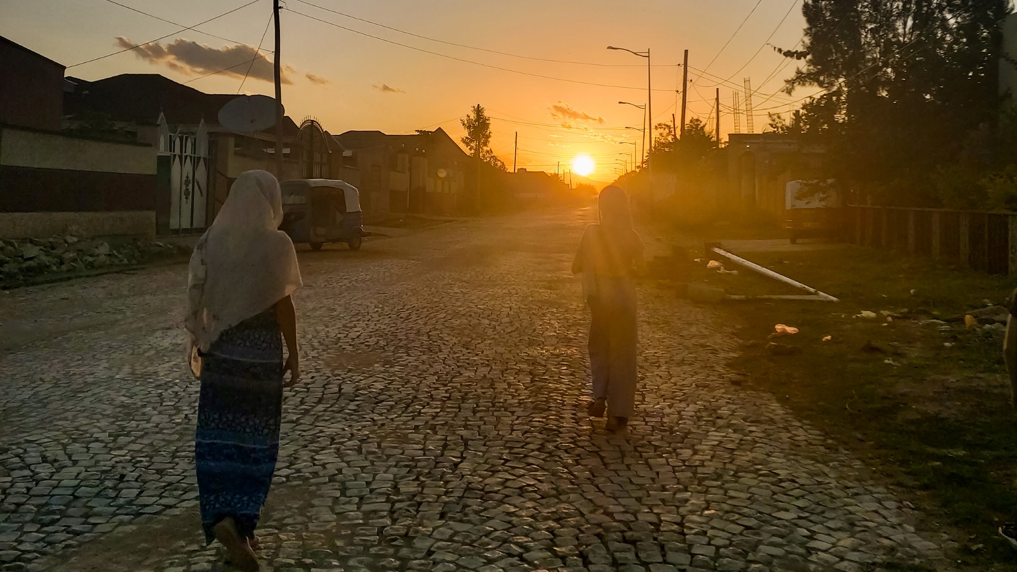 To kvinner i sjal går i gate i solnedgang