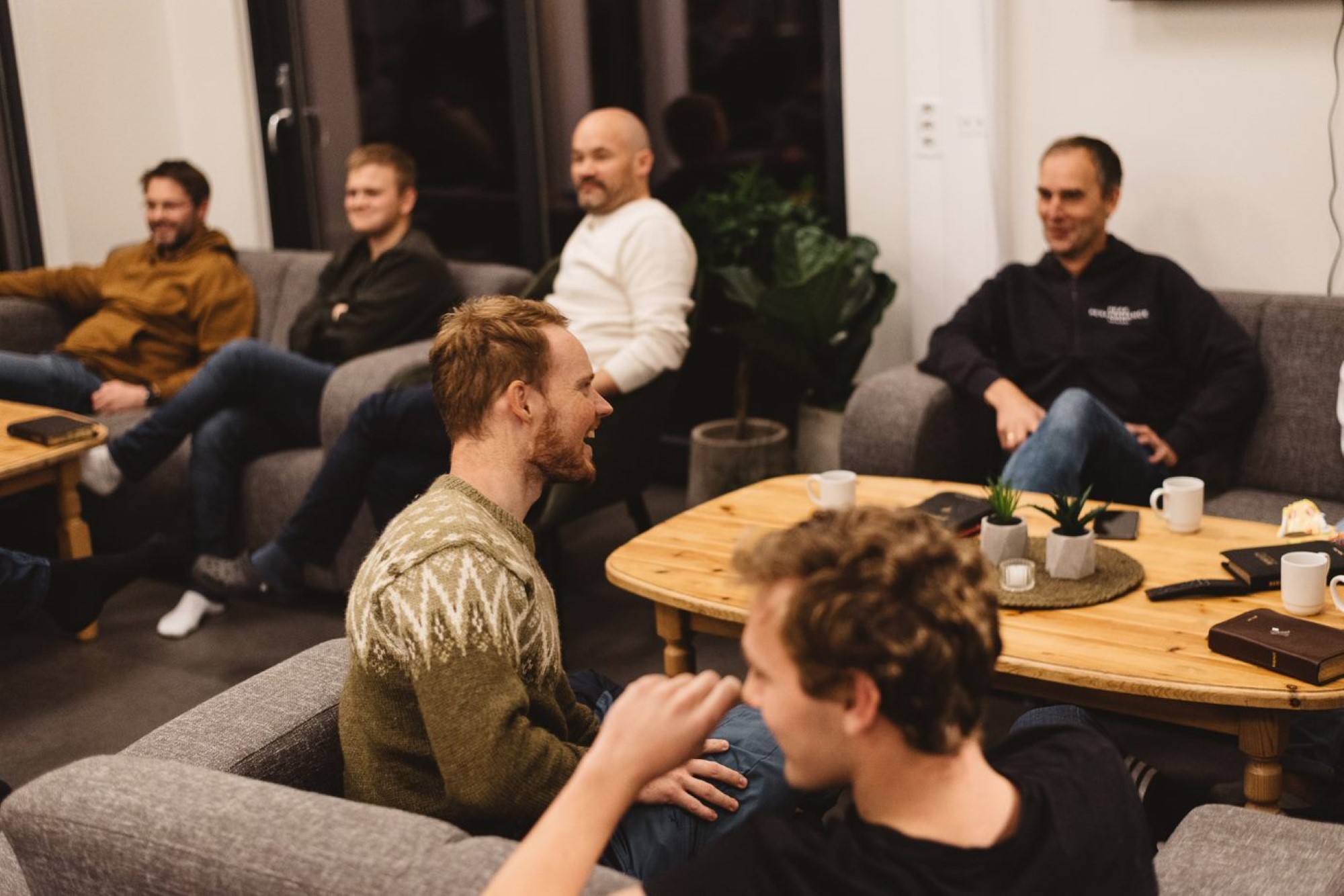 Flere menn sitter og prater i en sofagruppe