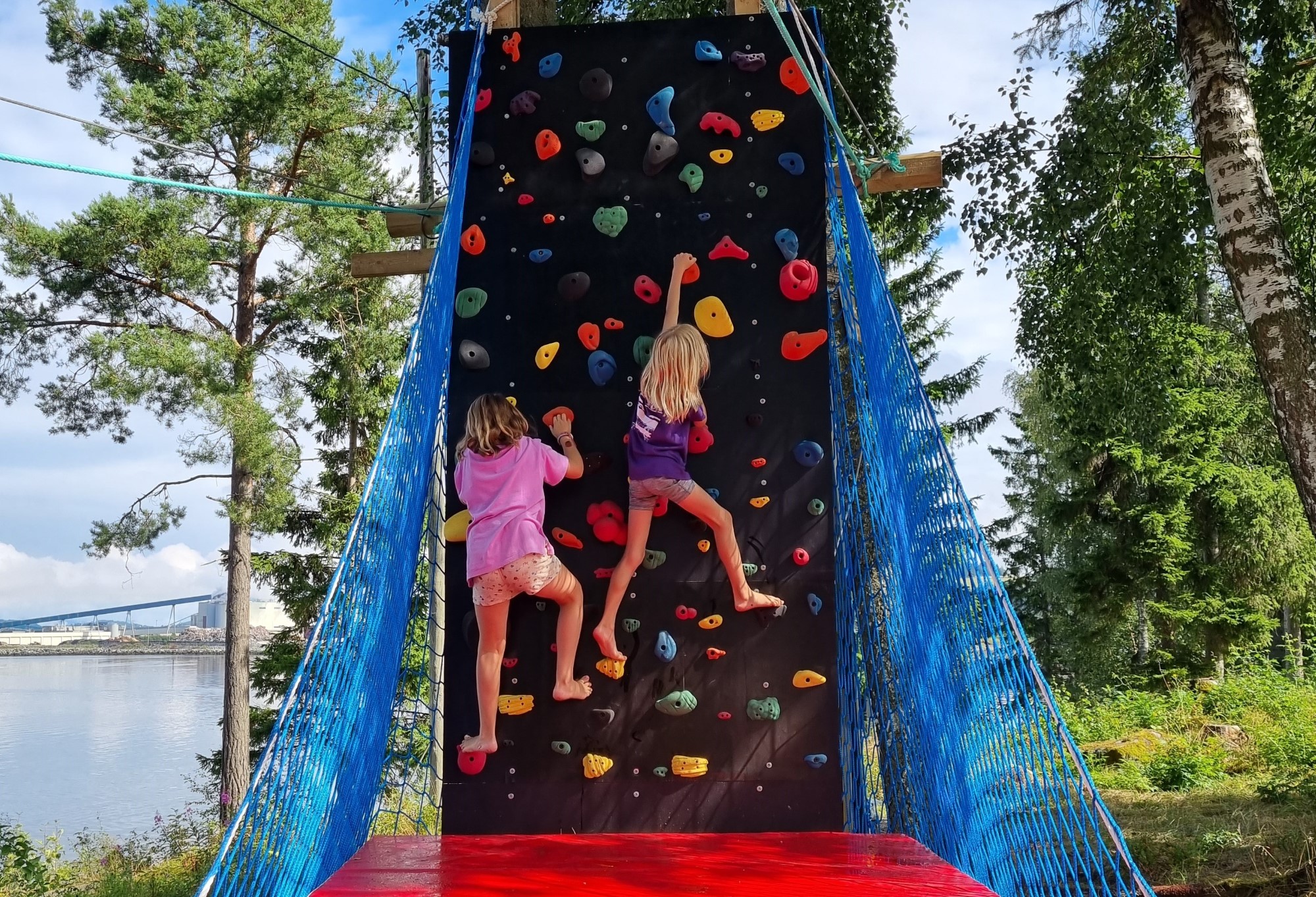 To jenter klatrer i klatrestativ ute