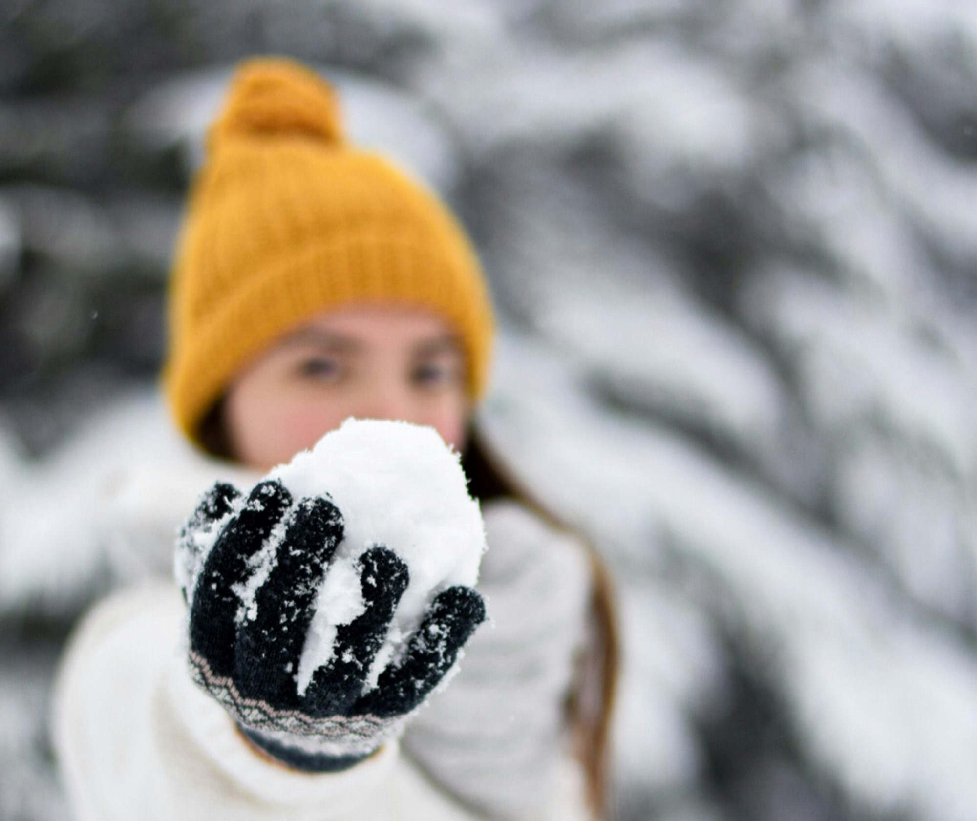 Jente med gul lue og snøball i hånden