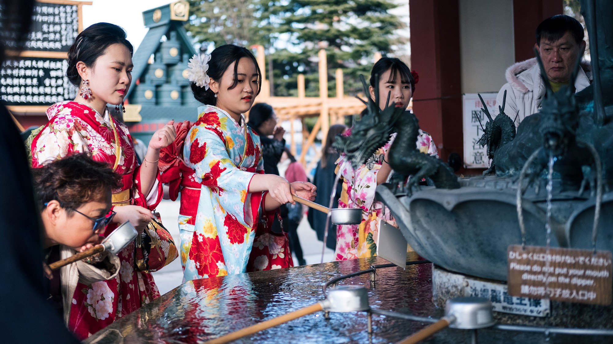 Kvinner i kimono ved fontene i tempel