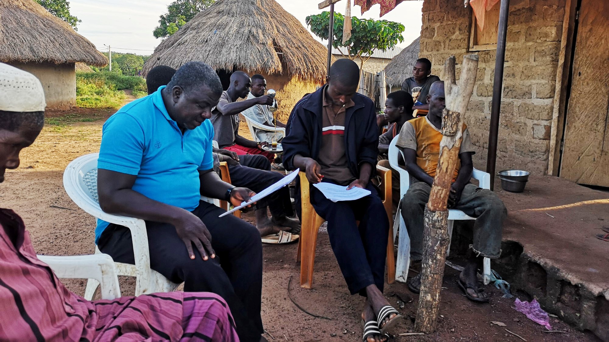 Menn på gårdstun lytter til radio