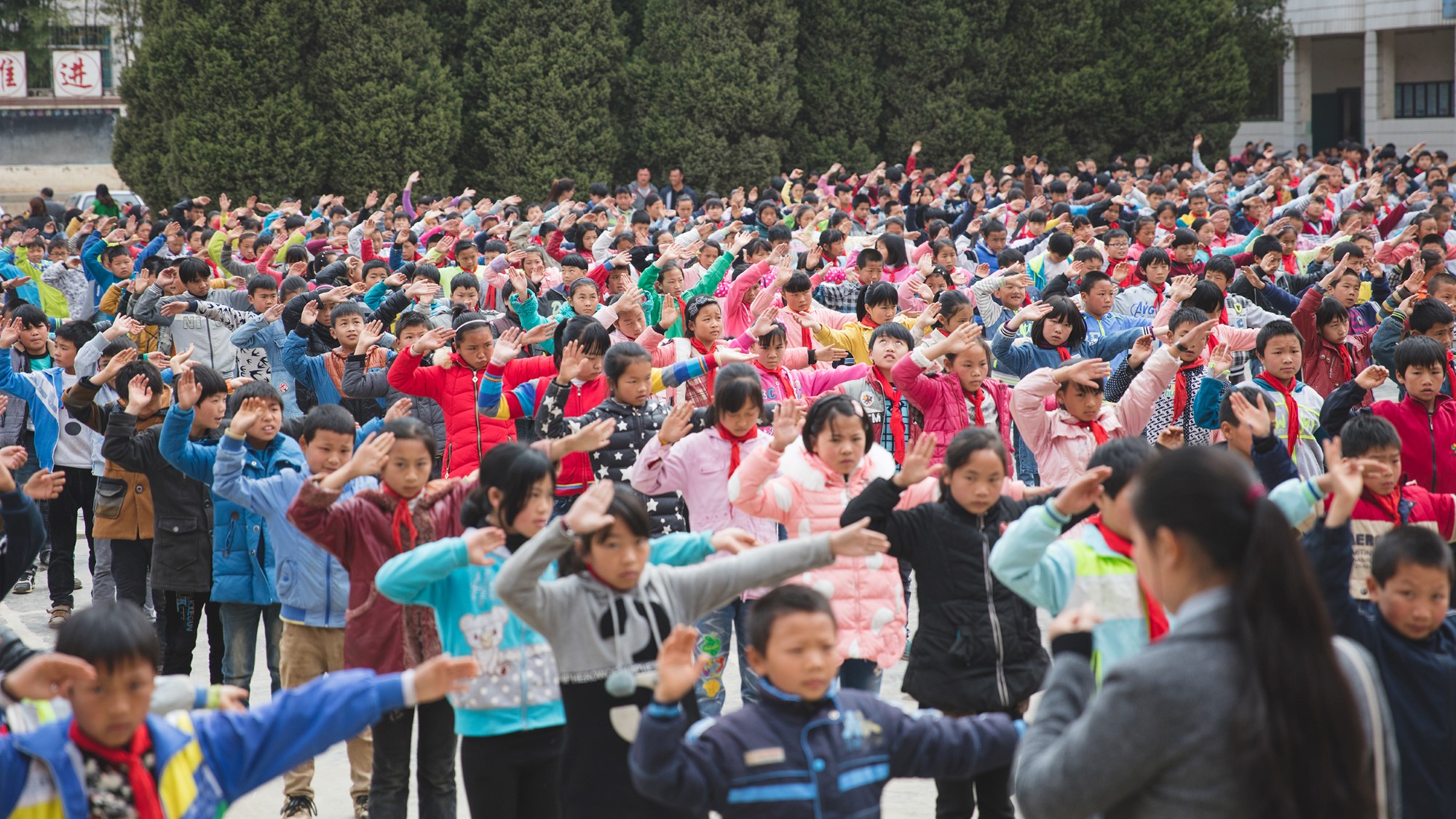 Hundrevis av skolebarn gjør synkrone bevegelser på skoleplassen
