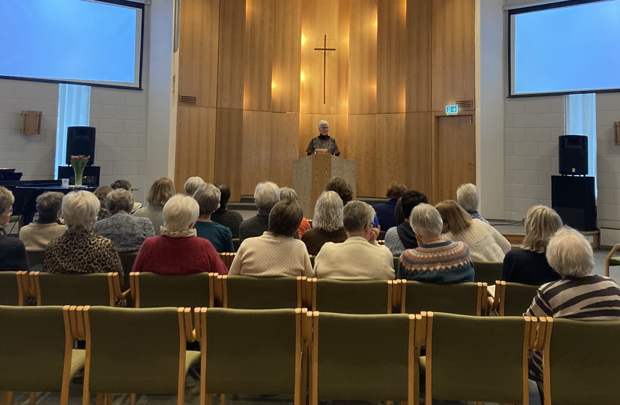 Bildet viser mange damer i en forsamling som sitter å lytter.