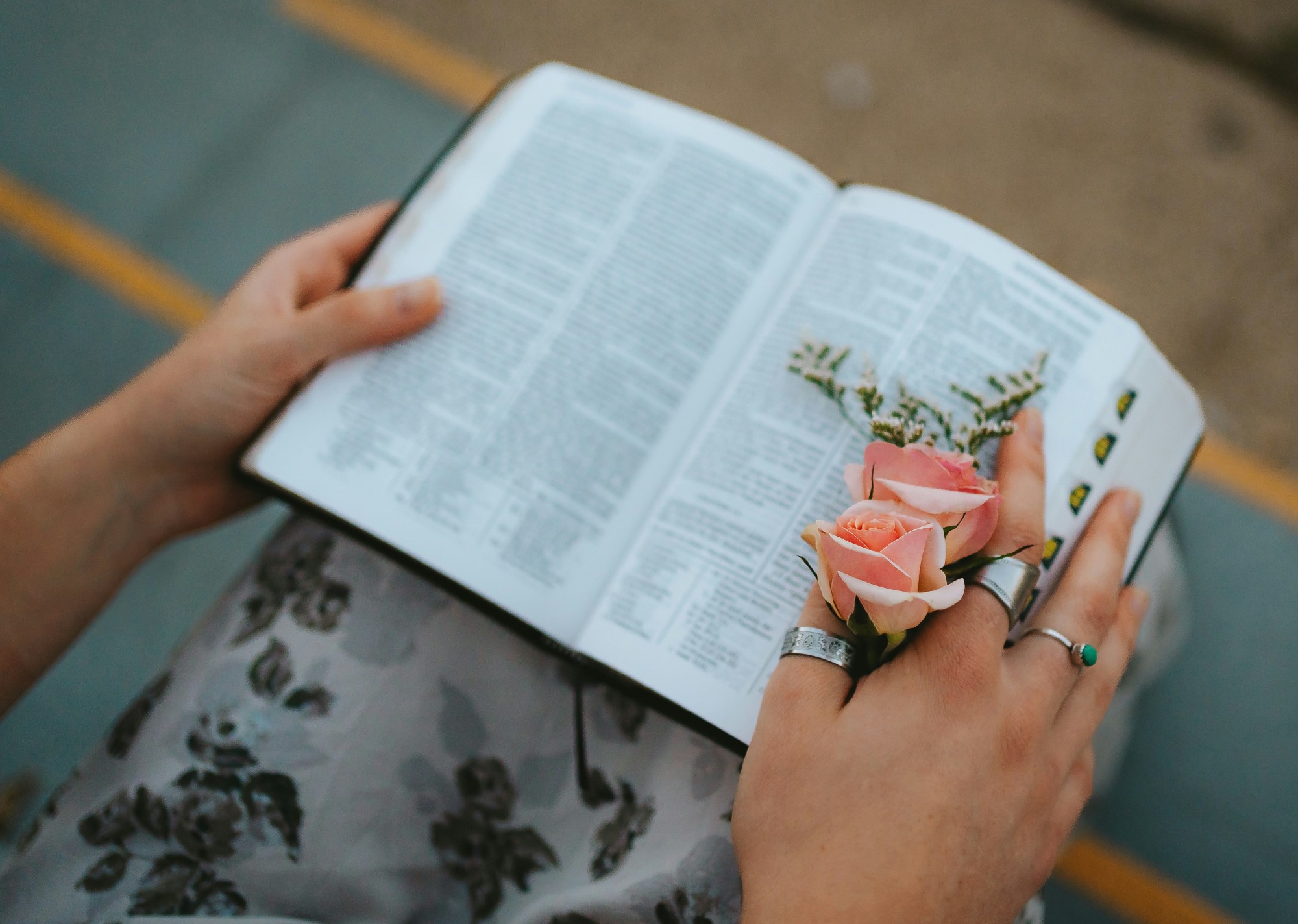 Dame holder bibel og blomst i fanget