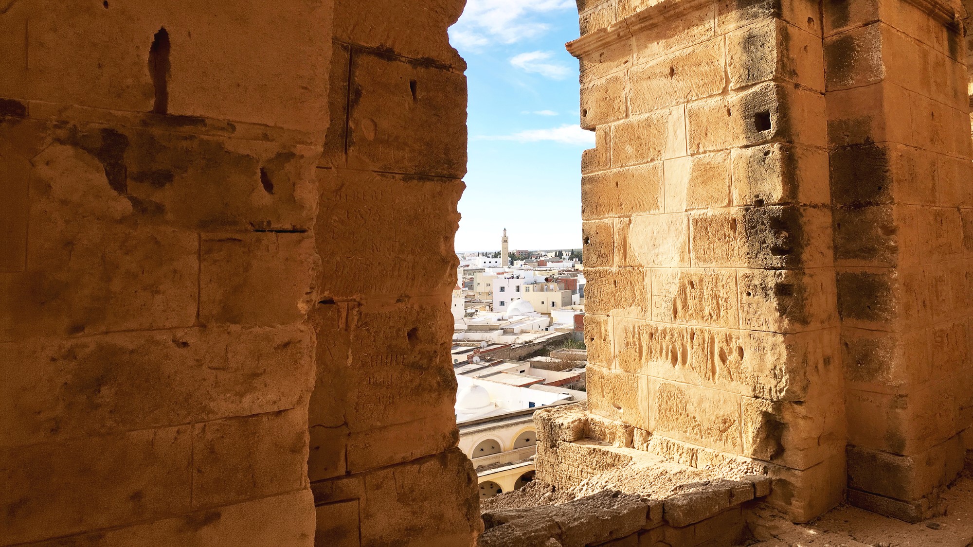 Vindusbue i gammel steinmur med utsikt over by