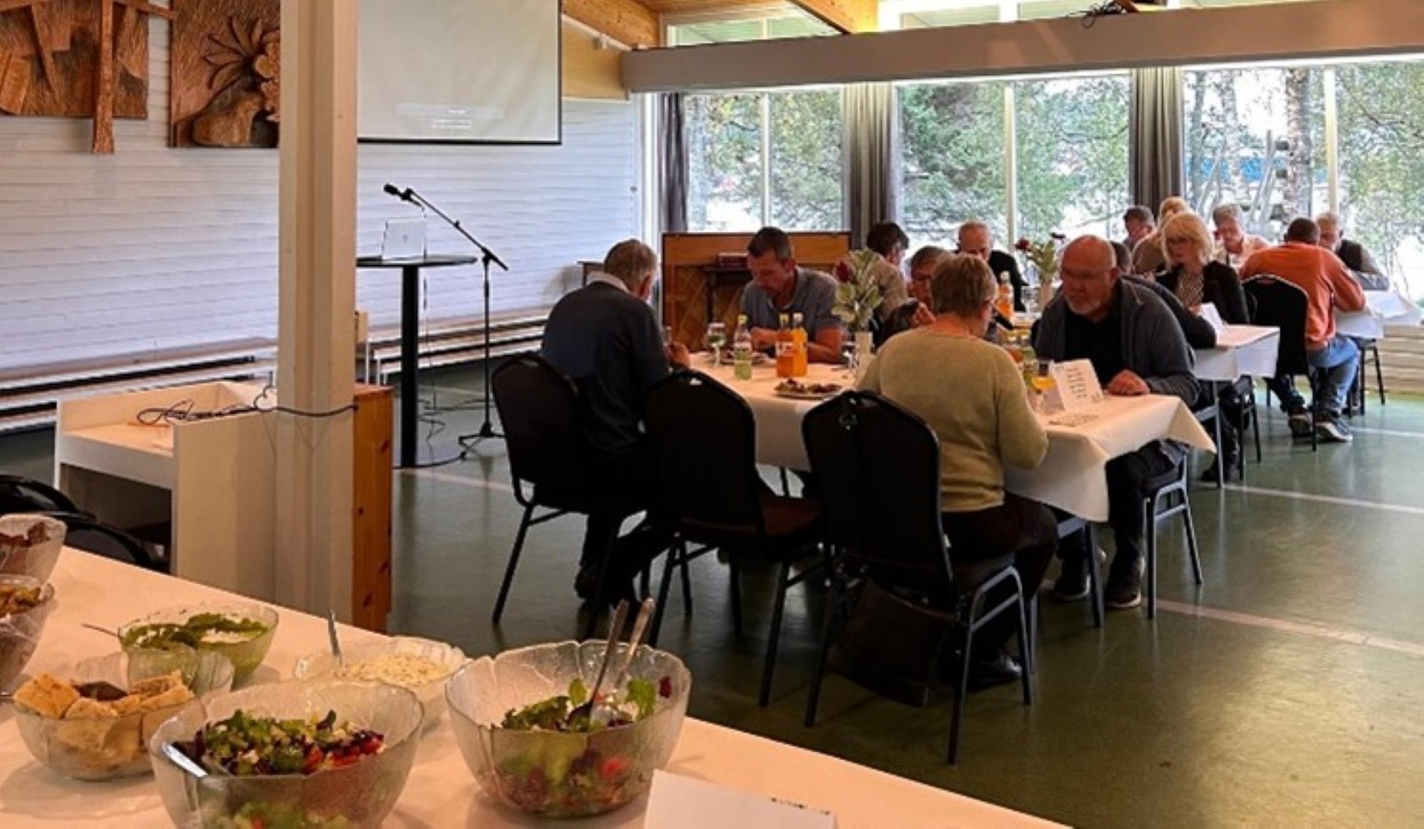 Bildet viser mange mennesker som sitter rundt festpyntet bord og spiser