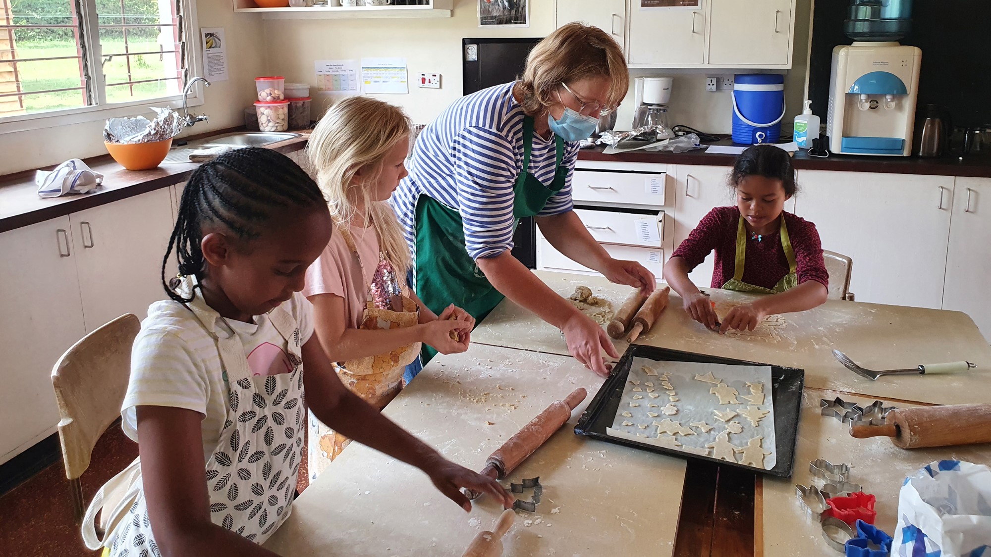 Barn og lærer baker julekaker på kjøkkenbord