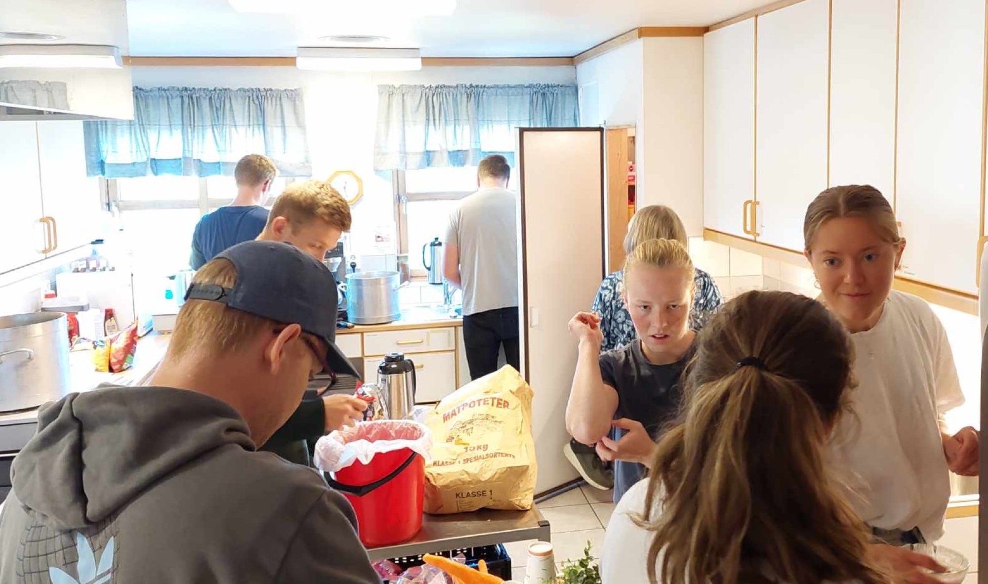 8 ungdommer lager mat på lite bedehuskjøkken