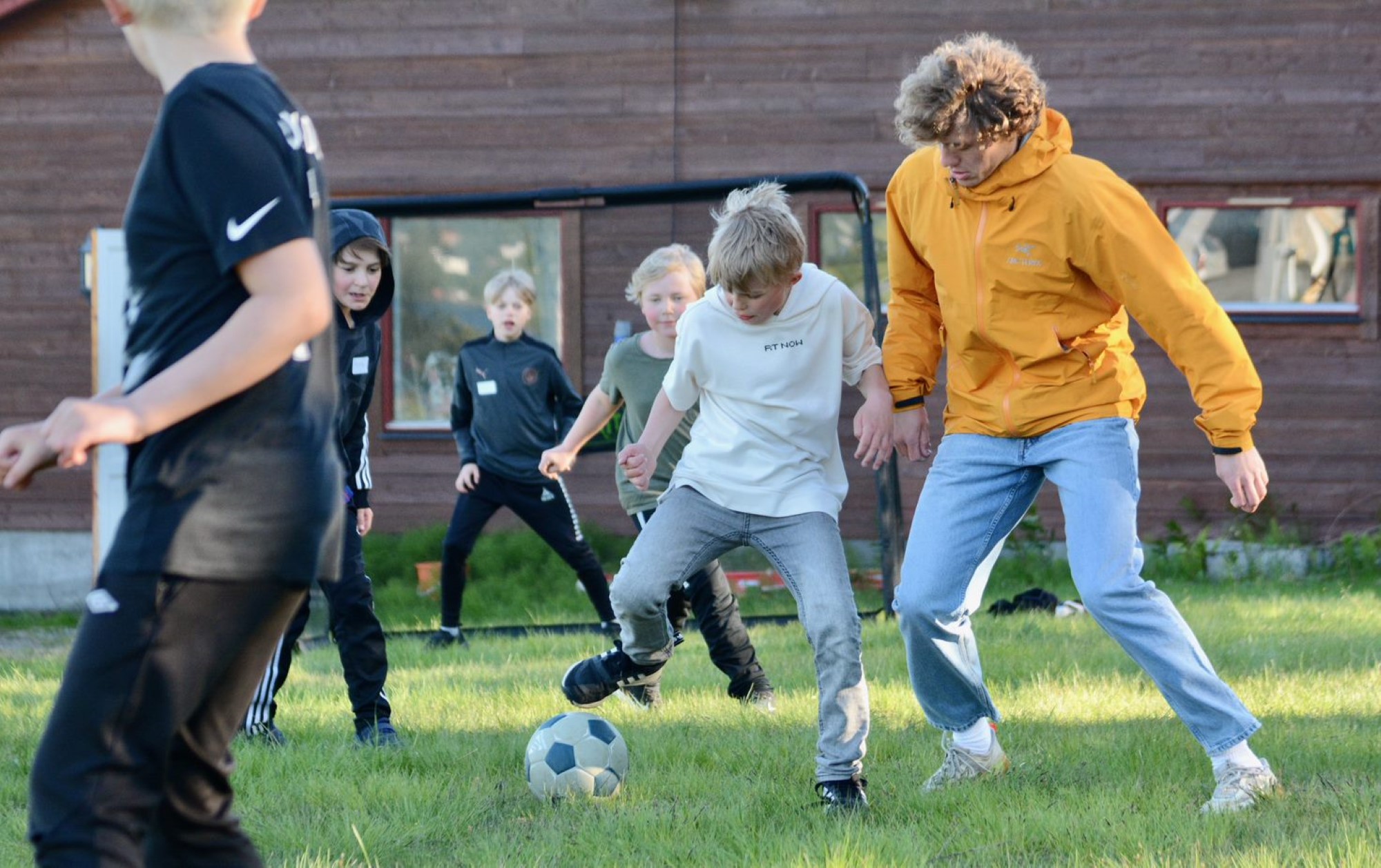 Barn som spiller fotball sammen med ledere