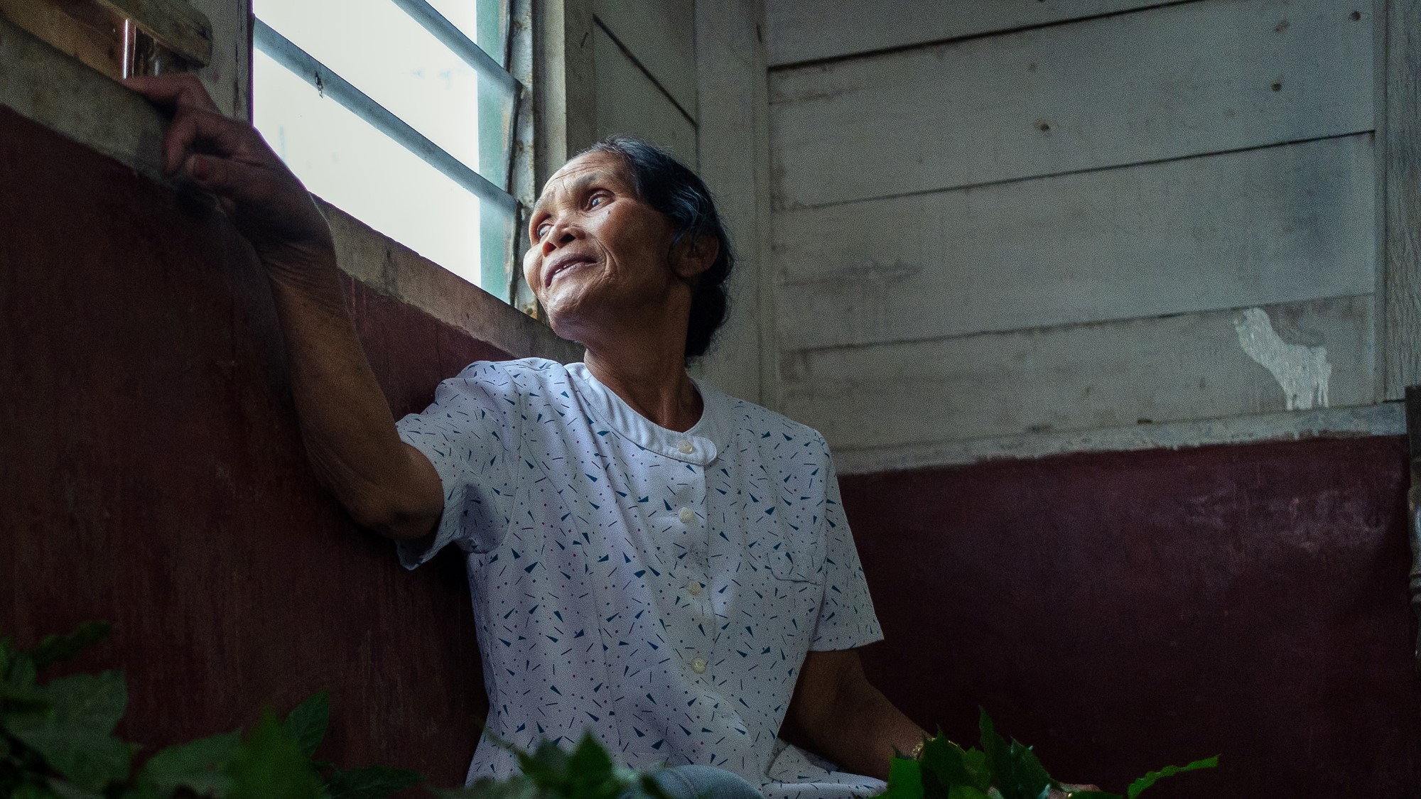 Eldre indonesisk kvinne ser ut vinduet