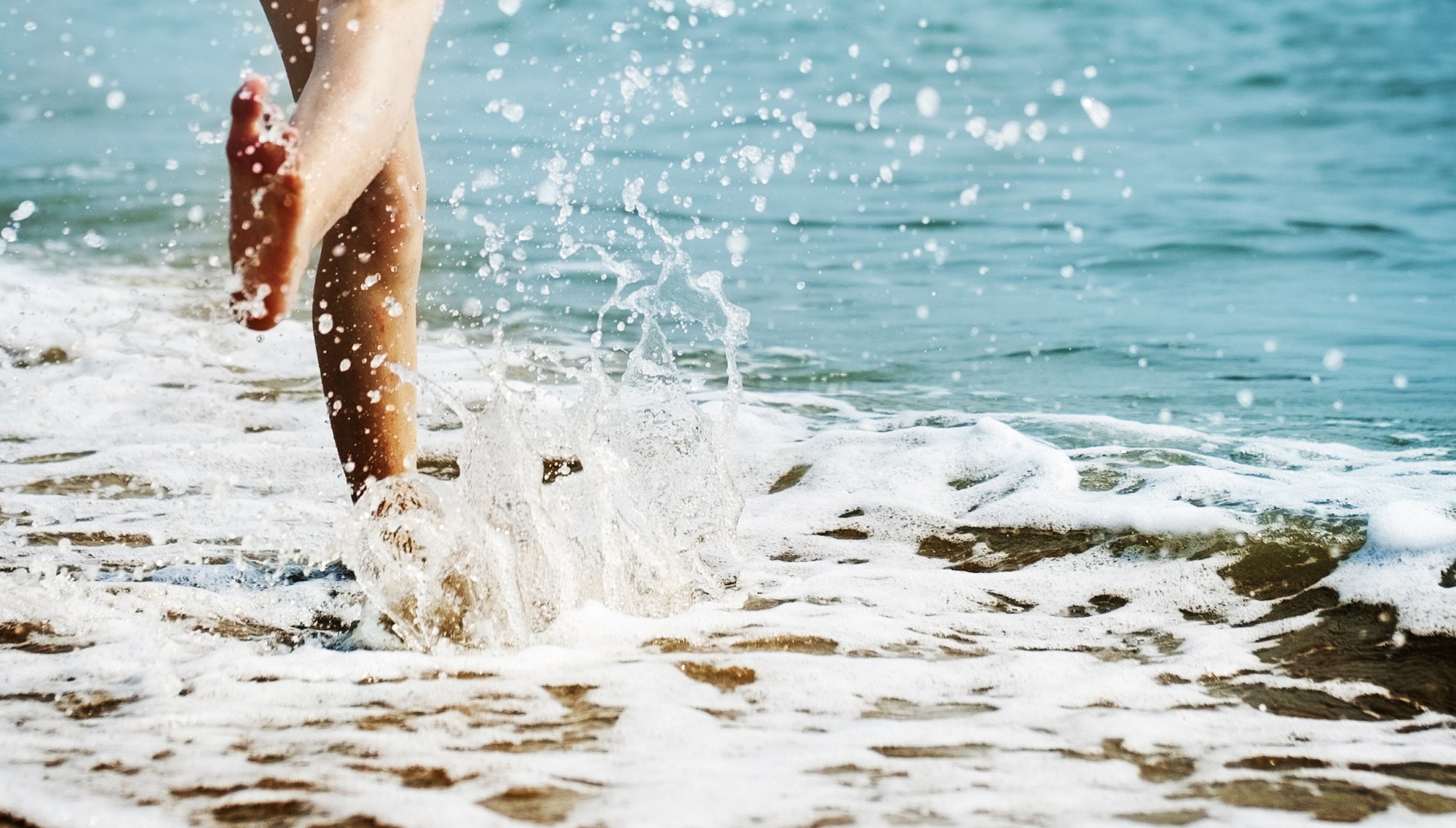 Jente sparker vann på strand
